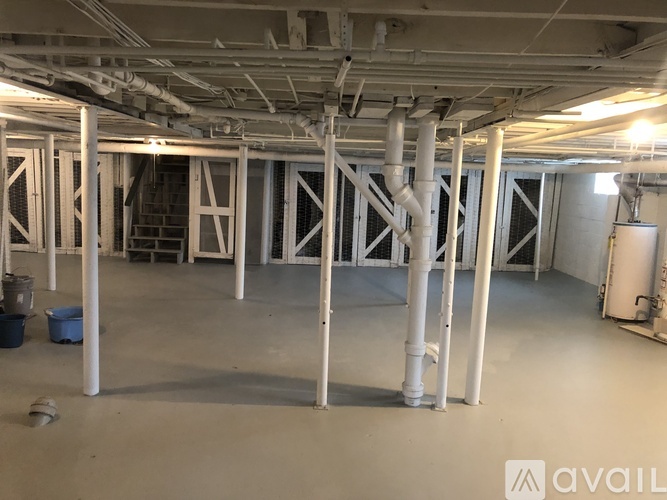A large, empty industrial space with white pipes and a concrete floor.