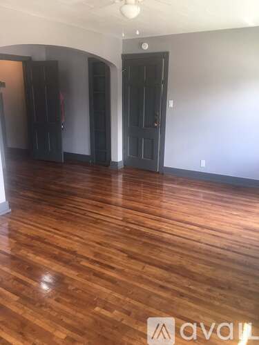 A room with wooden floors and two black doors.