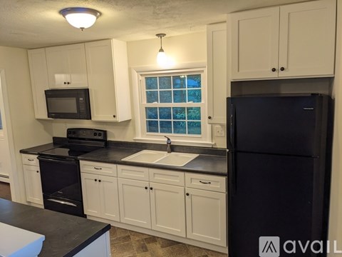 A kitchen with black appliances and white cabinets.