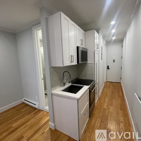 A kitchen with white cabinets and a wooden floor.