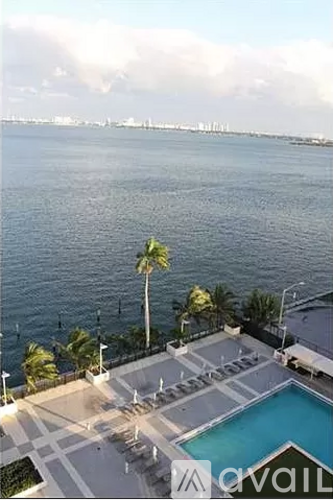 A pool area with a view of the water and a distant city skyline.