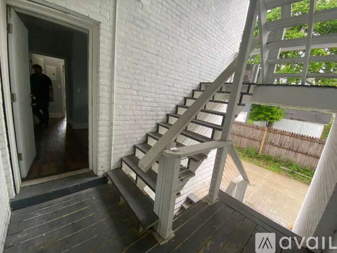 A person is standing in the doorway of a room with a white brick wall.