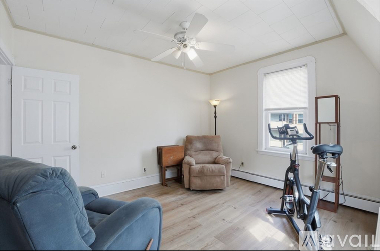A living room with a blue couch, a tan chair, and a stationary bike.