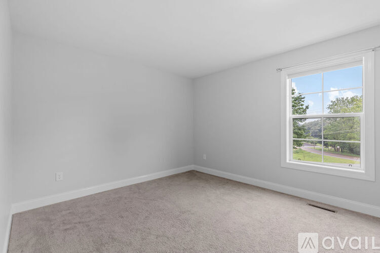 A room with a window showing a view of a fence and trees outside.
