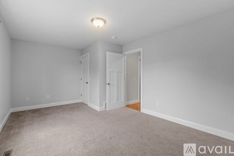 A spacious room with a carpeted floor and white walls.