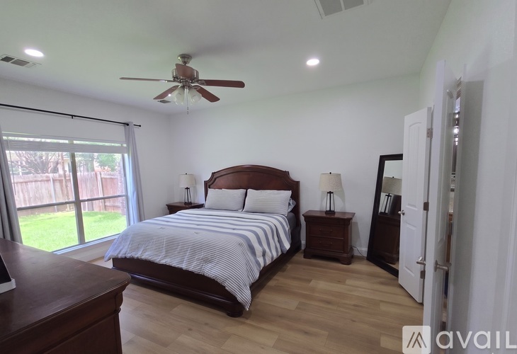 A bedroom with a large bed and a ceiling fan.
