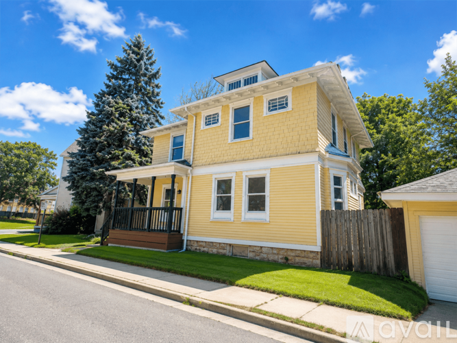 A yellow house with a black fence and a white garage door.