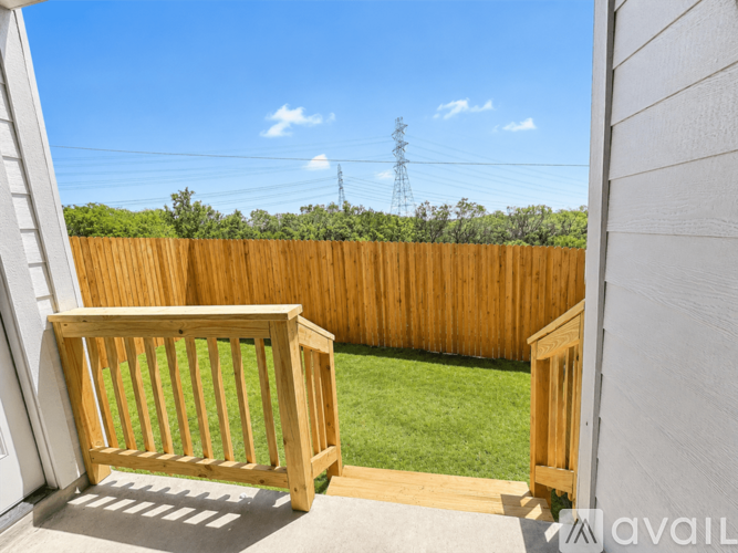 A wooden deck with a view of a grassy area and a power line tower.