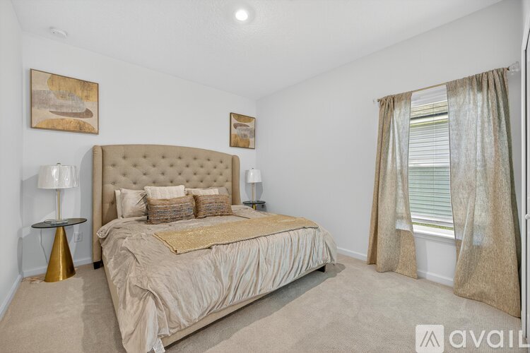 A bedroom with a large bed and a window with curtains.