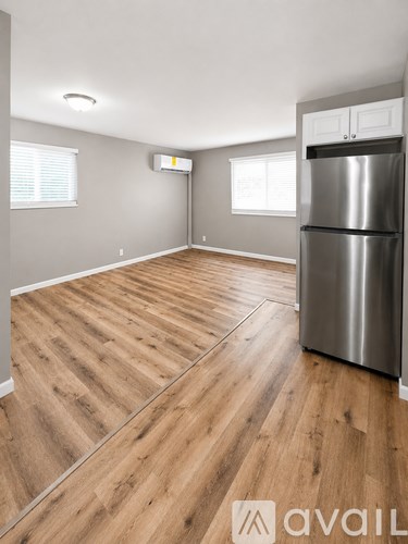 A kitchen with a wooden floor and a stainless steel refrigerator.