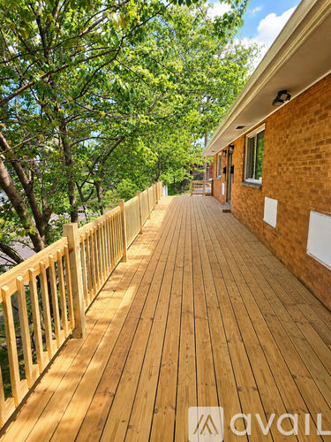 A wooden deck with a railing and trees in the background.