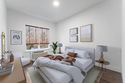 A bedroom with a large bed and a window with blinds.