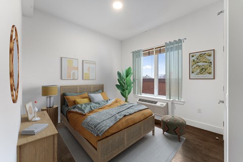 A bedroom with a bed, nightstand, and window.