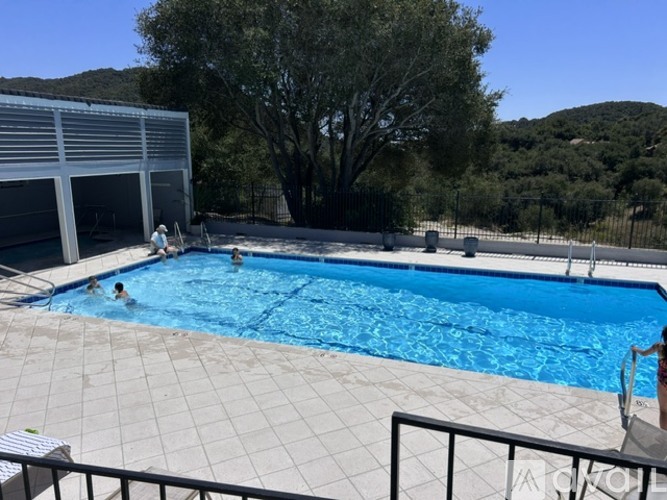 A swimming pool with people in it and a building in the background.