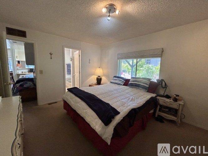 A bedroom with a bed, nightstand, and window.
