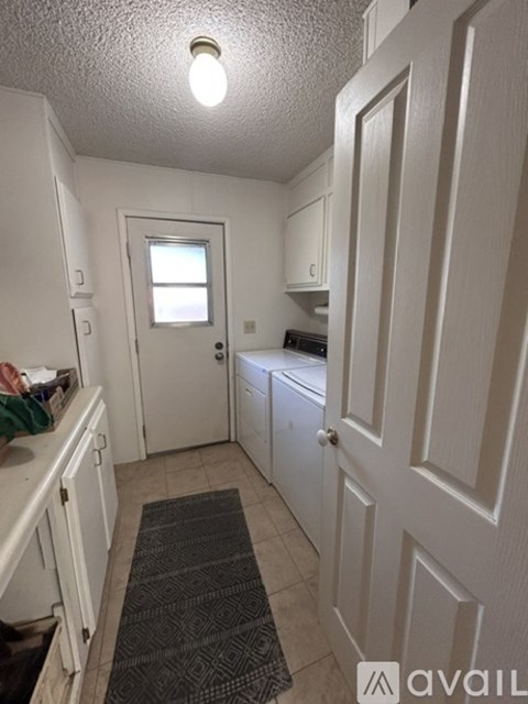 A kitchen with white cabinets and a door leading to a bathroom.