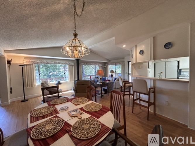 A dining room with a table set for six and a chandelier hanging from the ceiling.