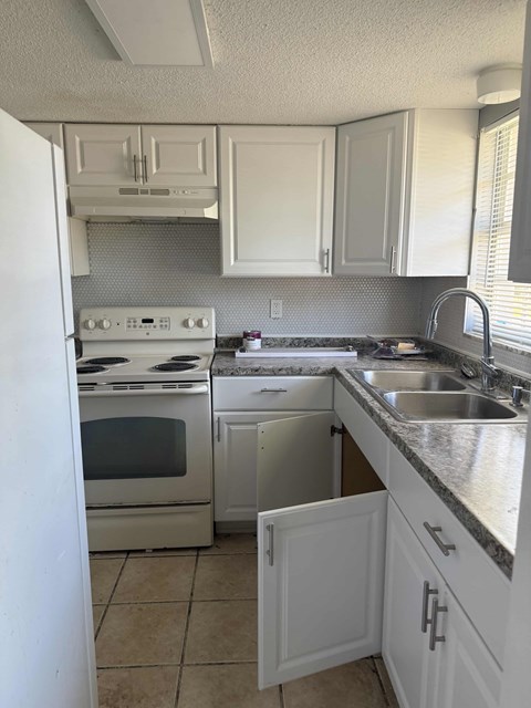 A kitchen with white cabinets and appliances.