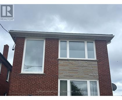 A brick house with a sign that says "Sutton Group Realty, Brokerage".