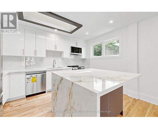 A modern kitchen with white cabinets and a marble island.