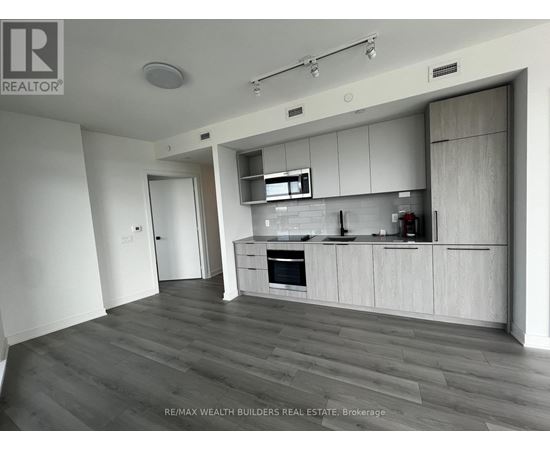 A modern kitchen with white cabinets and a wooden floor.