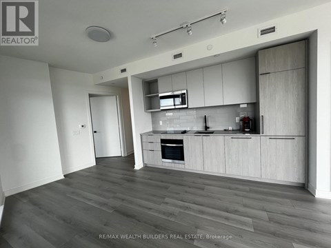 A modern kitchen with white cabinets and a wooden floor.