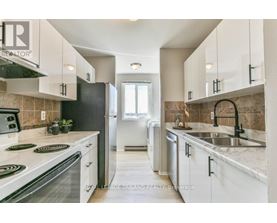 A kitchen with white cabinets and a black refrigerator.