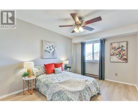 A bedroom with a bed, a ceiling fan, and two wall art pieces.