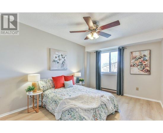 A bedroom with a bed, a ceiling fan, and two wall art pieces.