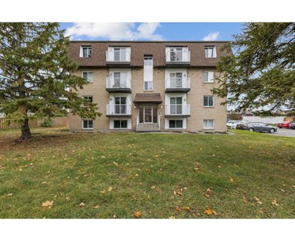 A large apartment building with a tree in front of it.