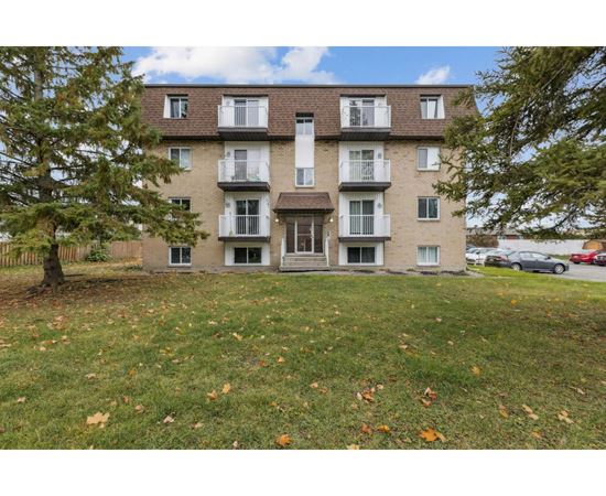 A large apartment building with a tree in front of it.