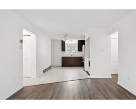A spacious room with wooden floors and white walls.
