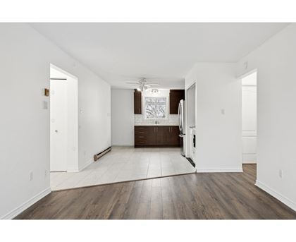 A spacious room with wooden floors and white walls.
