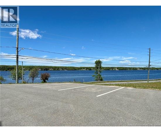 A parking lot with a lake in the background and a realtor logo in the corner.