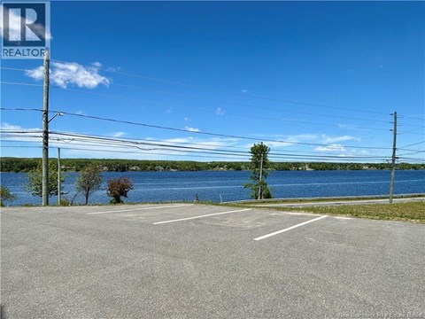 A parking lot with a lake in the background and a realtor logo in the corner.
