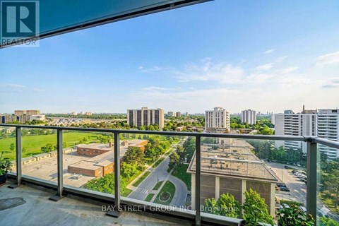A view from a balcony overlooking a cityscape with buildings and a road.