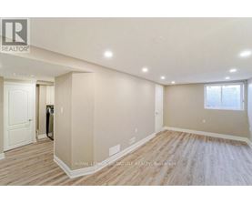 A spacious room with wooden flooring and a window with blinds.