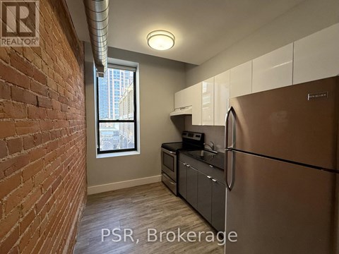 A kitchen with a stainless steel refrigerator and wooden flooring.