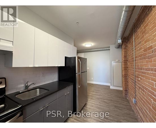 A kitchen with black countertops and a stainless steel refrigerator.