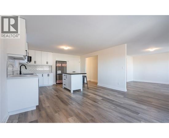 A spacious kitchen with white cabinets and a wooden floor.