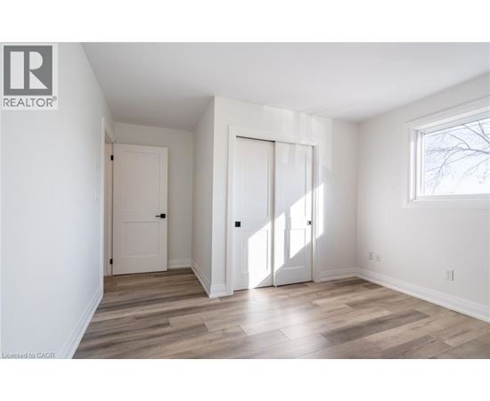 A room with a white door and a window with a view of trees outside.
