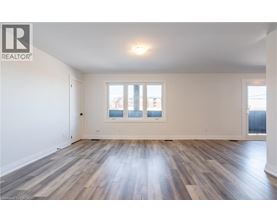 A spacious room with wooden flooring and a large window.