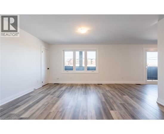 A spacious room with wooden flooring and a large window.