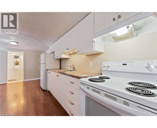 A white stove is in a kitchen with white cabinets and a white fridge.