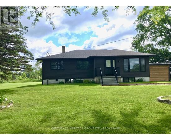 A black house with a white roof and a green lawn in front.