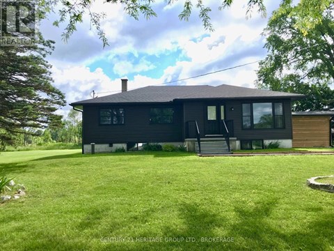 A black house with a white roof and a green lawn in front.