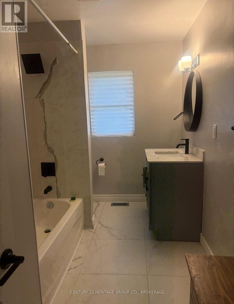 A bathroom with a sink, mirror, and bathtub.