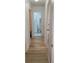 A hallway with wooden floors and white walls.