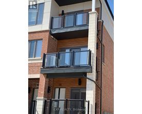 A balcony with black railings and a glass door is attached to a brick building.