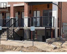 A black metal railing with a sign that says "RESERVED PARKING" is in front of a building.